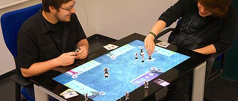 Chris Zimmerer (links) und Thomas Wedler (rechts) spielen das Strategiespiel "Quest" am Samsung SUR40 (Aufnahme: AG HCI)