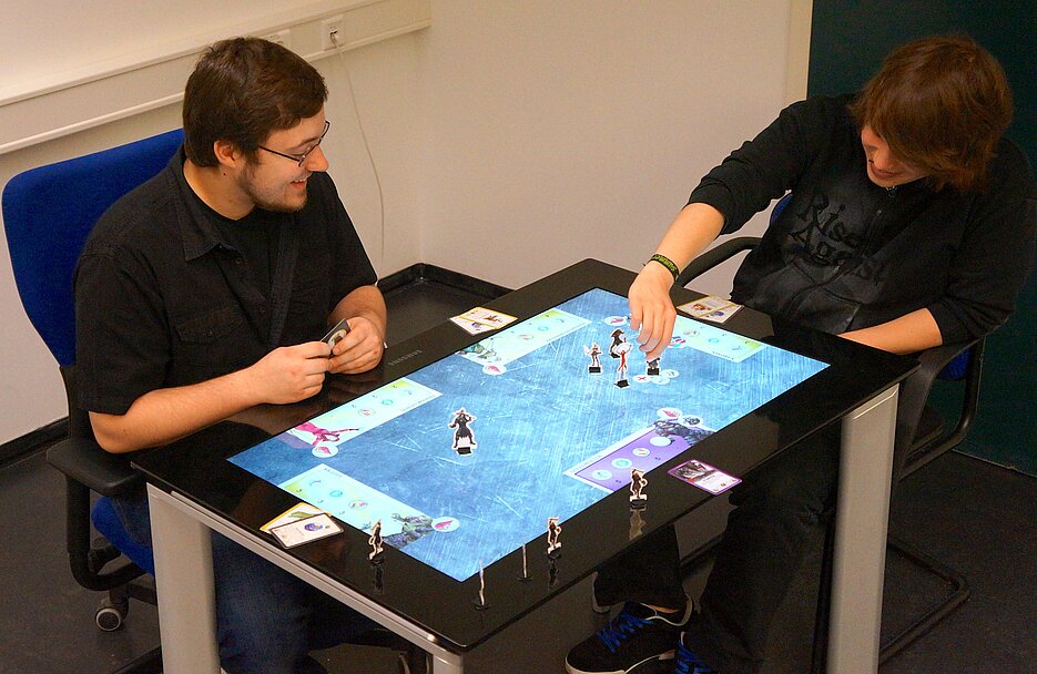 Chris Zimmerer (links) und Thomas Wedler (rechts) spielen das Strategiespiel "Quest" am Samsung SUR40 (Aufnahme: AG HCI)