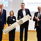 Michael Fuchs (re.) überreichte Stefanie Petermichl den „Schlüssel“ zum Neubau. Mit im Bild: Paul Pauli und Markus Blume. 