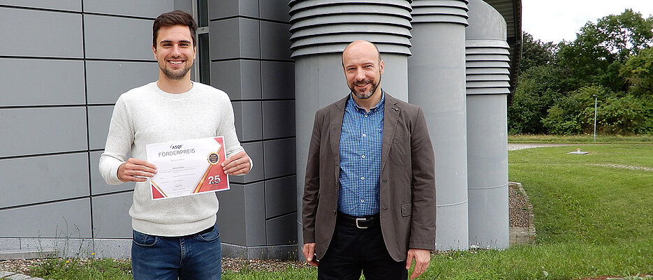 Der preisgekrönte Informatiker Martin Sträßer und Professor Samuel Kounev mit der Urkunde, die es für die herausragende Masterarbeit gab.