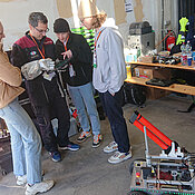 Die Studierenden (v.l.n.r.) Carolin Bösch, Julius Arzberger und Pascal Meyer leiten Analog-Astronaut Simone Paternostro (Zweiter v.r.) beim Test des Handbedienungsgeräts mit Touchscreen mit seinem Handschuh an. 