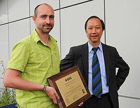 Die Würzburger Informatiker Tobias Hoßfeld (links) und Phuoc Tran-Gia mit der Auszeichnung, die sie von der IEEE Communications Society bekommen haben. (Foto: Robert Emmerich)